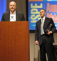 Jon Reed, vp global engineering for Genentech (at the podium) with Jim McGlade, chairman of the FOYA committee