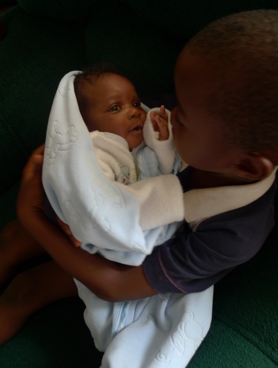 A young boy and his baby sister at a health centre in Zambia. The Ministry of Health has tapped IBM to provide 2,190 clinics with improved access to 200 life saving drugs. Photo Credit: UNICEF Zambia